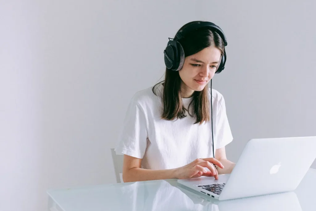Mujer con auriculares realizando un examen de inglés en el portátil