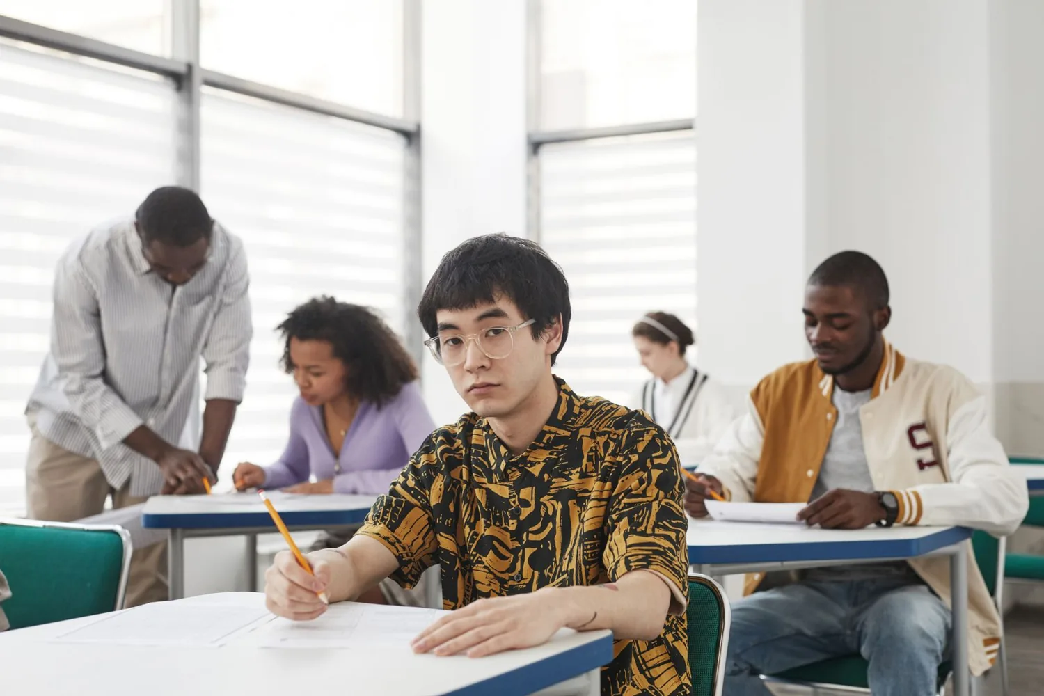 Estudiantes realizando un examen de inglés en un aula con supervisor