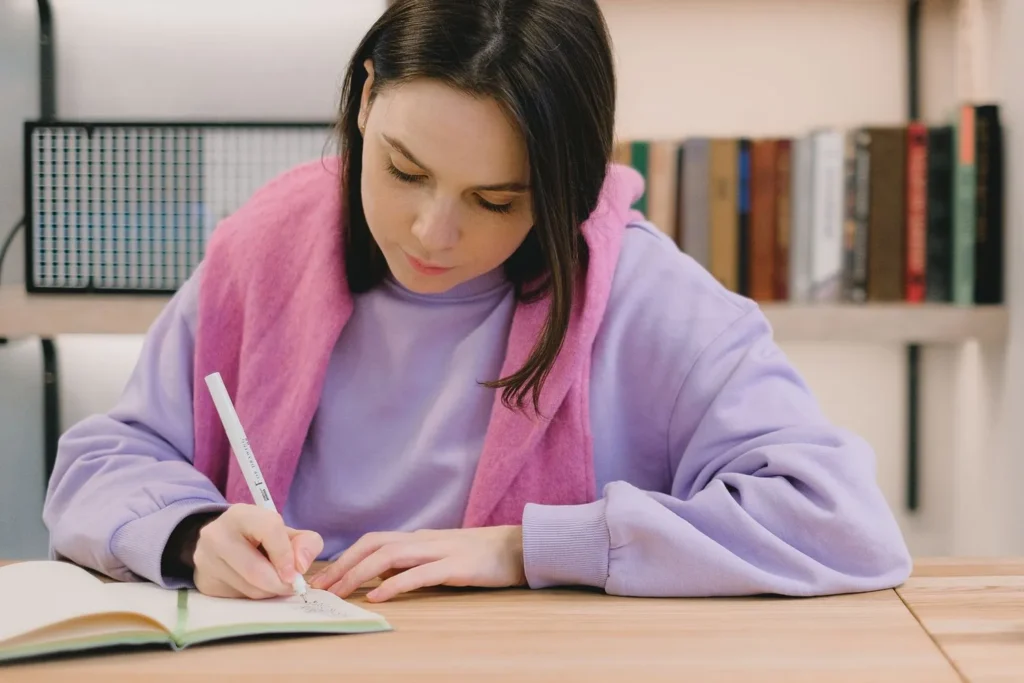 Candidata escribiendo en un cuaderno mientras prepara el examen de inglés C2